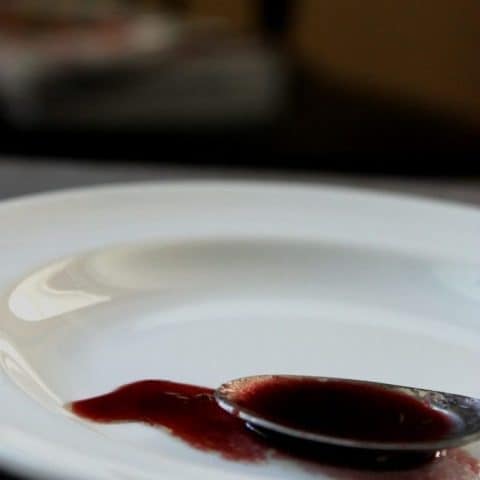 Close up of Red Grape Reduction in a spoon and smeared on a white plate