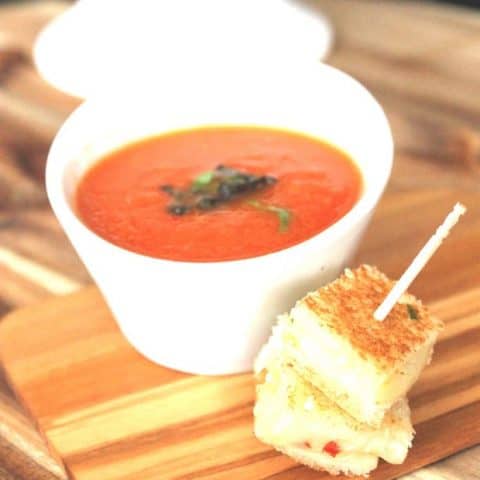 Summer Grilled Tomato Soup in a white bowl and grilled cheese bites on a cutting board