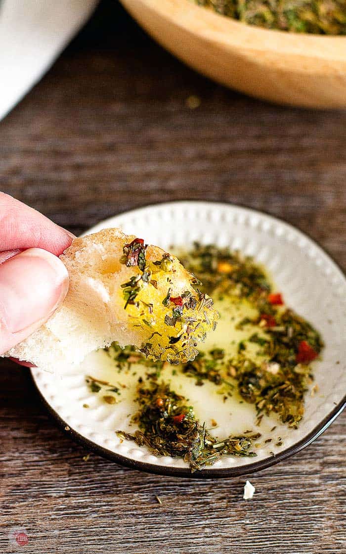 dipping a piece of bread in oil with Italian seasoning
