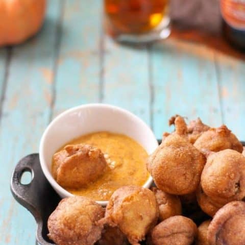 Overhead of andouille sausage corn dog bites and a small bowl of mustard in a black serving dish