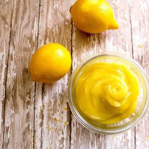 overhead shot of Homemade 10 Minute Lemon Curd in a glass bowl with 2 lemons on a table