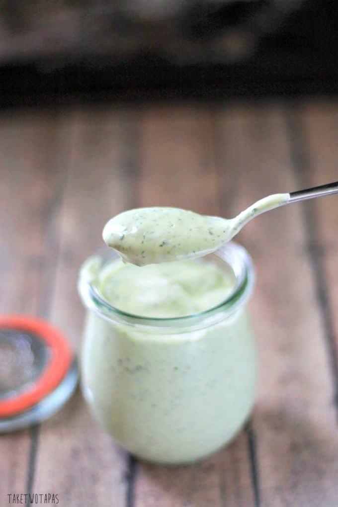 Side view of Cilantro Ginger Avocado Cream on a spoon above the jar of the creama