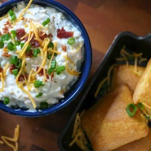 Overhead of flaky crescent bombs in a cast iron serving dish and crack dip in a blue bowl