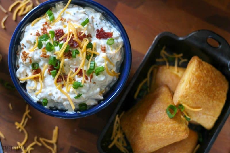 Overhead of flaky crescent bombs in a cast iron serving dish and crack dip in a blue bowl