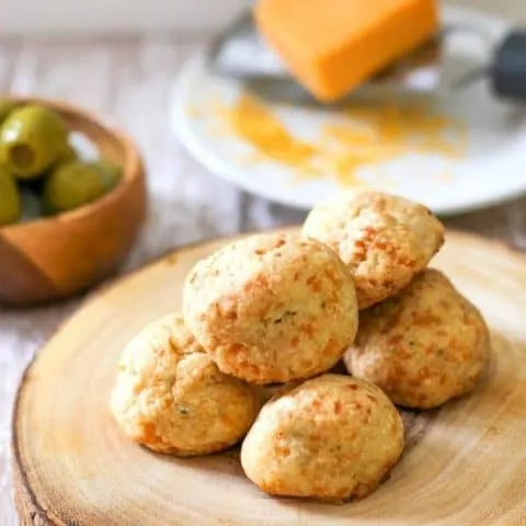 Close up of Blue Cheese Jalapeno Truffles on a wood platter with olives and cheese in the background.