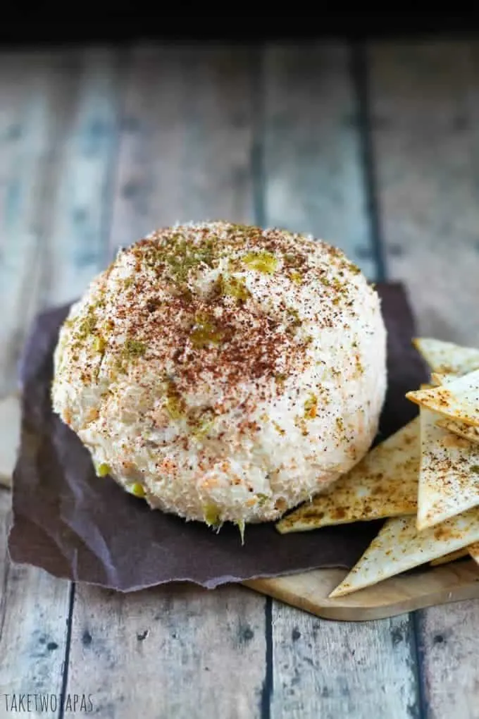 Overhead of Mexican Cheese Ball with spicy tortilla chips on a wood cutting board.