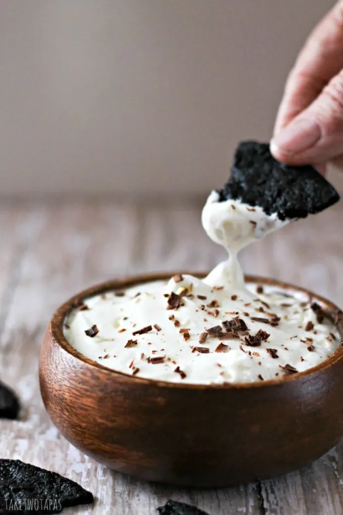 Hand dipping a chocolate wafer in to the oreo cheesecake dip