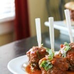 Side view of Lamb Meatballs on a white plate with appetizer forks in them