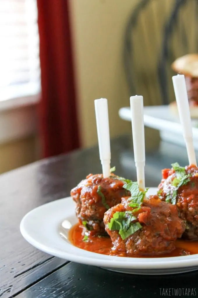 Side view of Lamb Meatballs on a white plate with appetizer forks in them