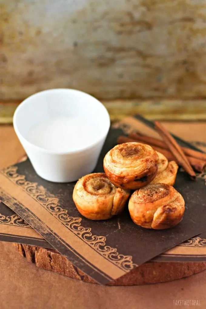 These mini cinnamon roll bites are quickly made with the help of puff pastry. Sprinkled with brown sugar and baked until golden brown, they are crispy on the outside and flaky on the inside. Top them off with vanilla glaze for the perfect bite! Mini Puff Pastry Cinnamon Roll Bites Recipe | Take Two Tapas | #PuffPastry #CinnamonRolls #Breakfast