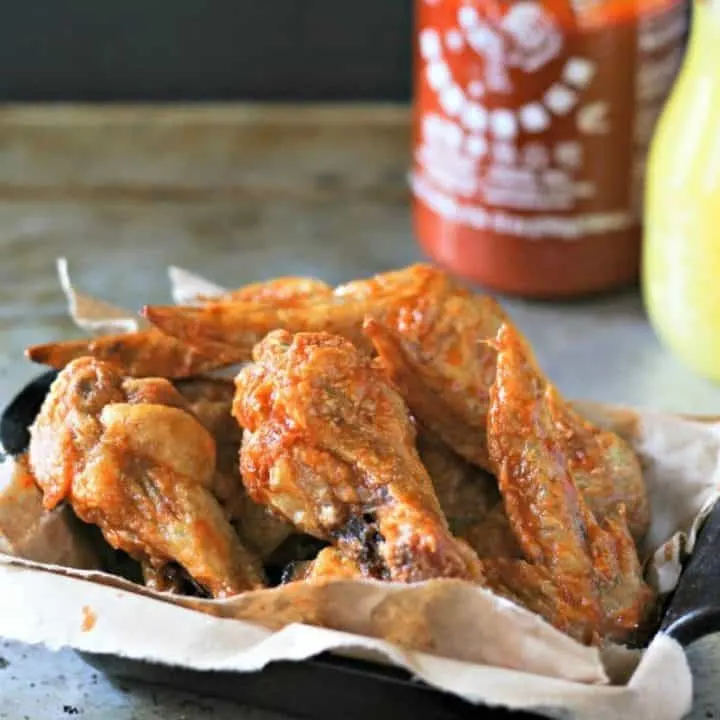 close up of Spicy Sriracha Pineapple Chicken Wing in a black serving dish