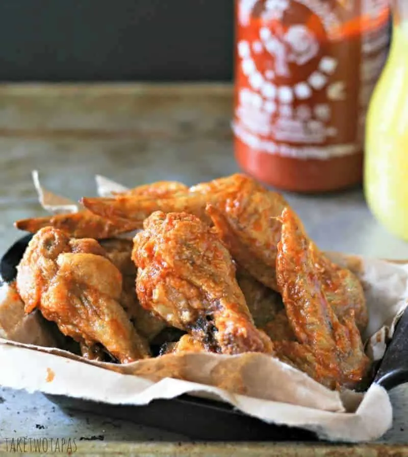 close up of Spicy Sriracha Pineapple Chicken Wing in a black serving dish