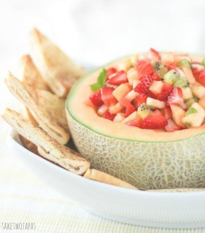 Salsa in a cantalope with chips in a white bowl