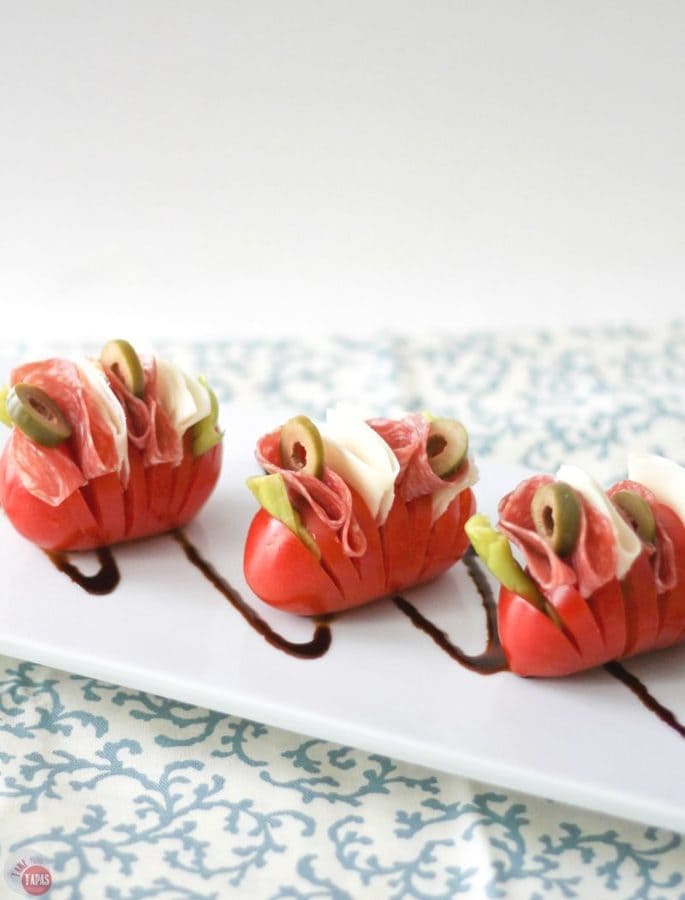Want a fun twist on an antipasto salad? Try these Hasselback Antipasto Tomatoes! All the delicious ingredients of an antipasto salad all tucked into a tomato. Antipasto Hasselback Tomatoes Recipe | Take Two Tapas | #Hasselback #Tomatoes #Healthy #Tapas #Antipasto #Salad
