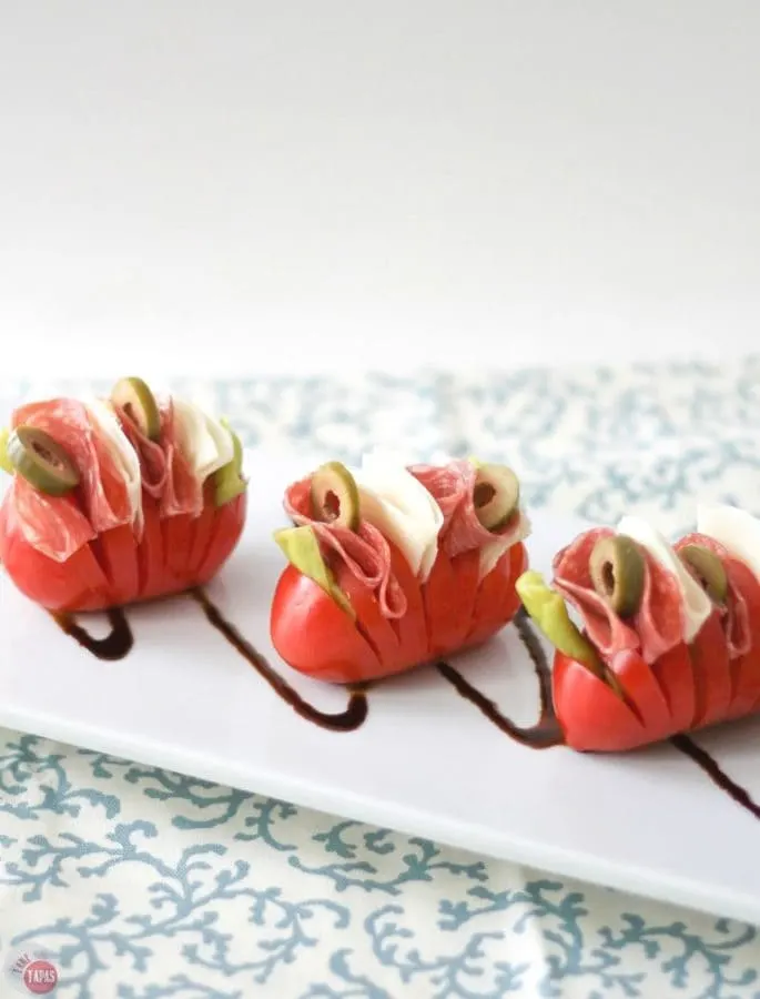 Want a fun twist on an antipasto salad? Try these Hasselback Antipasto Tomatoes! All the delicious ingredients of an antipasto salad all tucked into a tomato. Antipasto Hasselback Tomatoes Recipe | Take Two Tapas | #Hasselback #Tomatoes #Healthy #Tapas #Antipasto #Salad