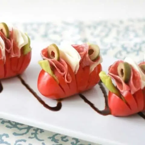 Close up of Hasselback tomatoes on a white platter