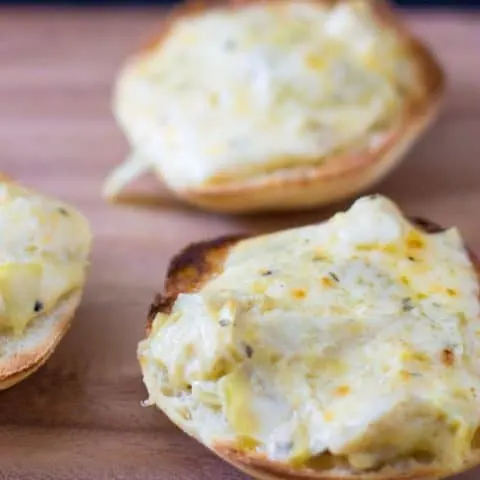 Close up of Warm and gooey cheese toast is made even tastier with roasted garlic and tangy marinated artichokes.