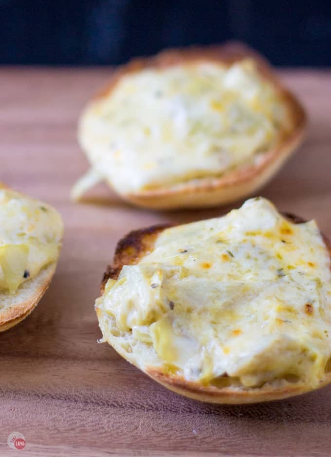 Close up of Warm and gooey cheese toast is made even tastier with roasted garlic and tangy marinated artichokes.