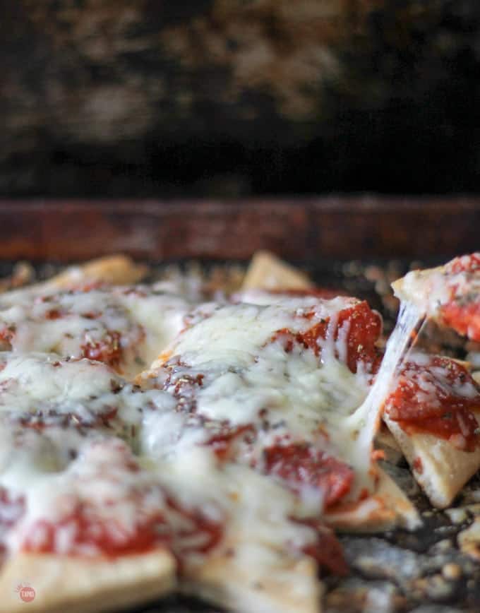 close up of a pizza nacho being take from the sheet pan