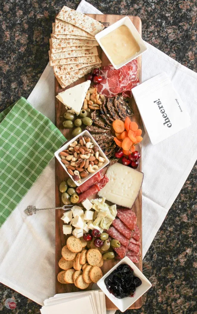 Overhead picture of the antipasto cheese board. Full of fruits, meats, cheeses, nuts, and olives.