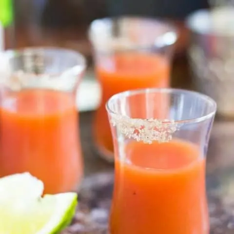 side view of Bloody Mary Shots on a wood surface