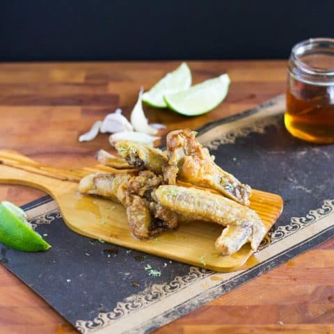 Side view of Garlic honey lime chicken wings on a cutting board