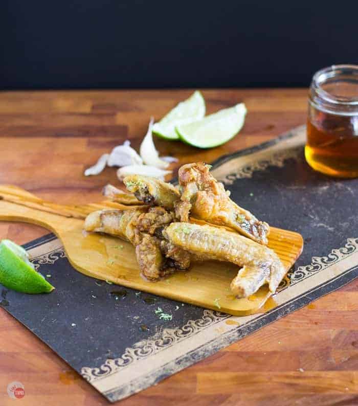 Side view of Garlic honey lime chicken wings on a cutting board