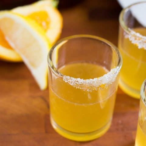 Orange Sidecar Cocktail Shot on a wood surface with orange slices in the back.