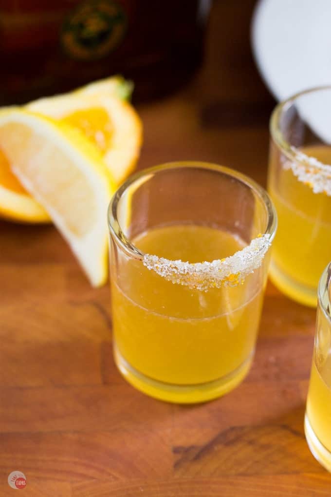 Orange Sidecar Cocktail Shot on a wood surface with orange slices in the back.