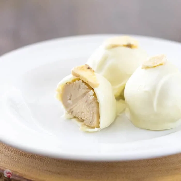 Close up of Creamy Banana Pudding Truffles on a white plate and one has a bite taken out of it.