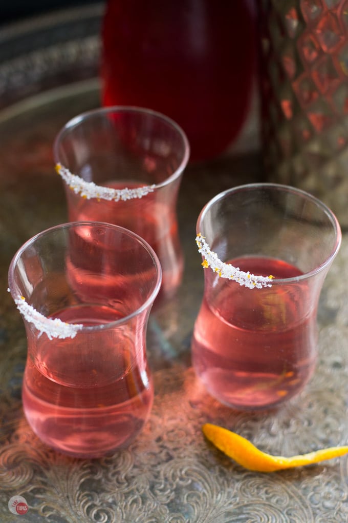 3 shot glasses with cosmopolitan in them on grey table
