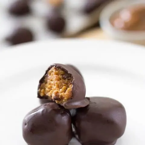 Side view of Dulce de Leche fireball truffles on a white plate.