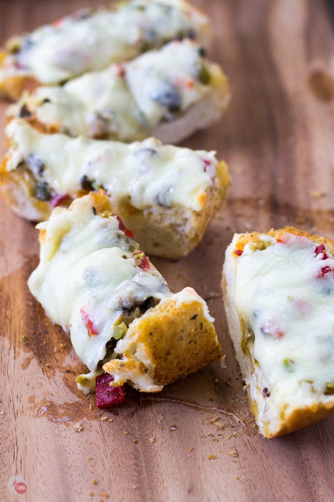 Up close of sliced cheesy olive bread on a wood surface.