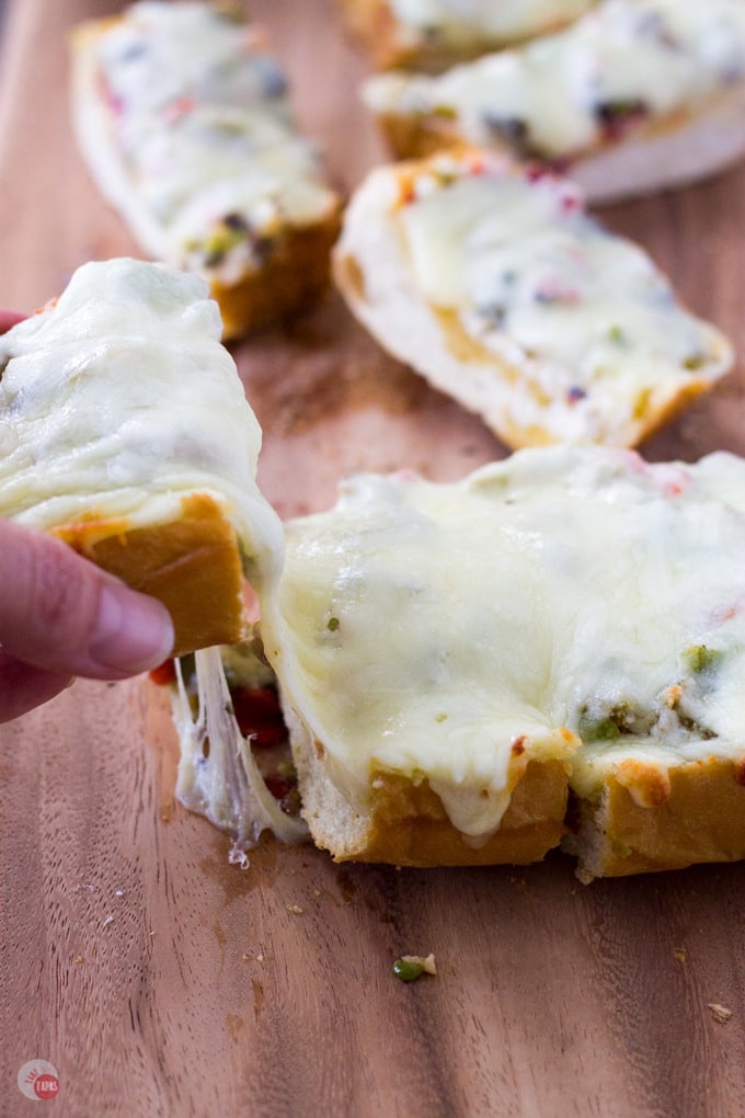 Hand taking a piece of the cheesy olive bread.