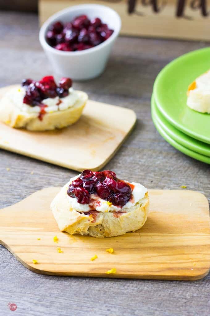 roasted cranberry ricotta crostini on a mini cutting board