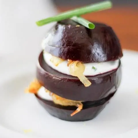 Close up of a pickled beet napoleon on a white plate.