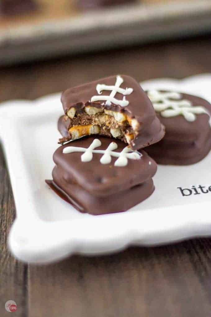 Big Game Reese's Pretzel Football Cookies |on a white square plate. One has a bite out of it.