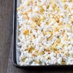 A tropical snack mix of dried pineapple, toasted coconut chips, roasted macadamia nuts, drizzled in white chocolate. Perfect as a slightly healthier snack mix for those days when you are craving everything! Tropical Hawaiian Popcorn Mix Recipe | Take Two Tapas | #Popcorn #Hawaiian #PopcornSnack #HealthySnacks #TrailMix
