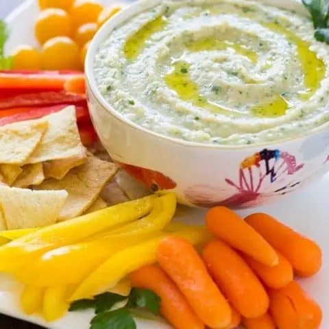 White Bean Parsley Hummus in a white bowl and assorted vegetables on a white platter
