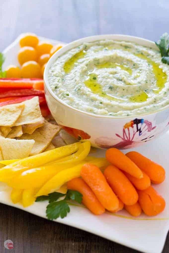 White Bean Parsley Hummus in a white bowl and assorted vegetables on a white platter