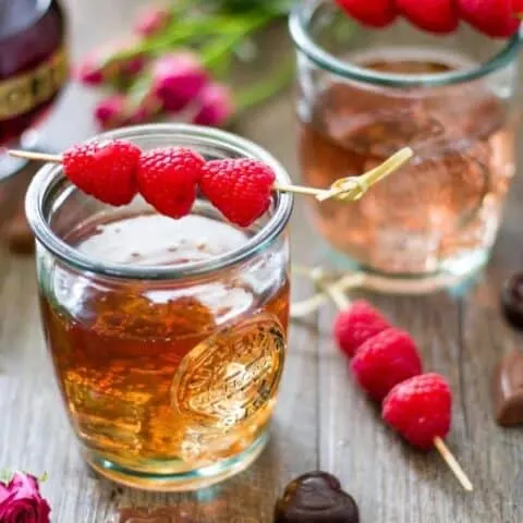 Close up of Raspberry love cocktail with raspberry garnish on a wood surface