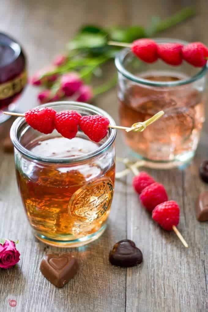 Close up of Raspberry love cocktail with raspberry garnish on a wood surface