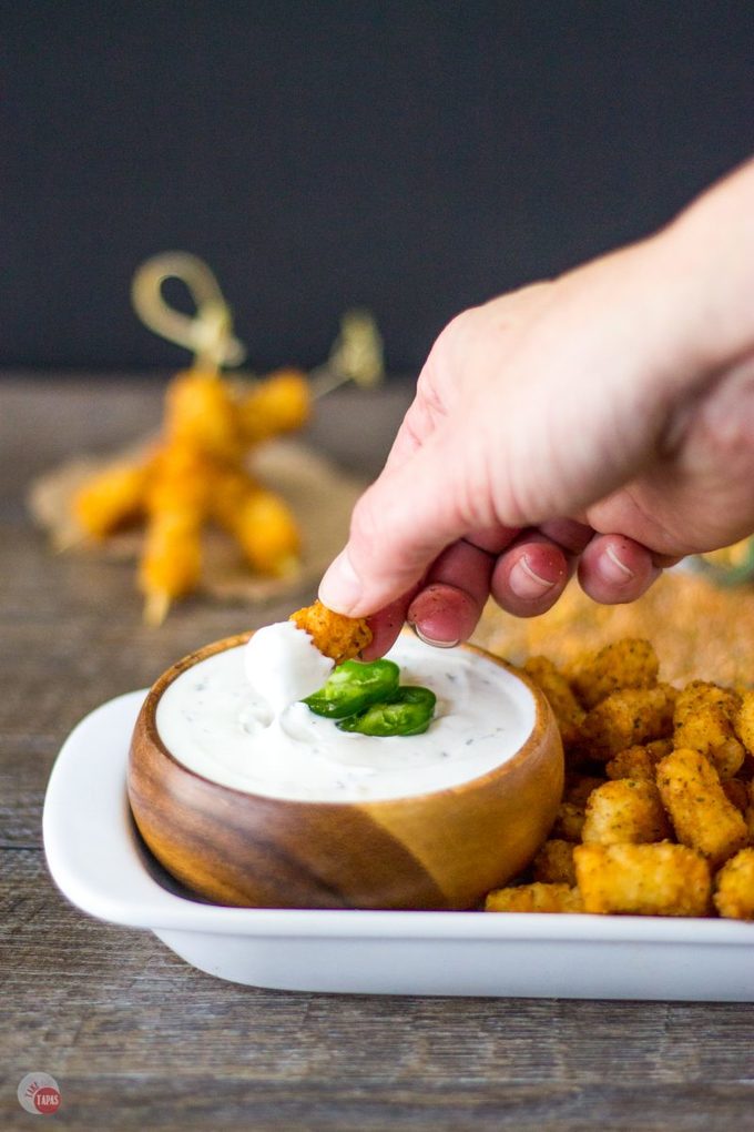 Hand dipping a tater tot in the jalapeno ranch dip.