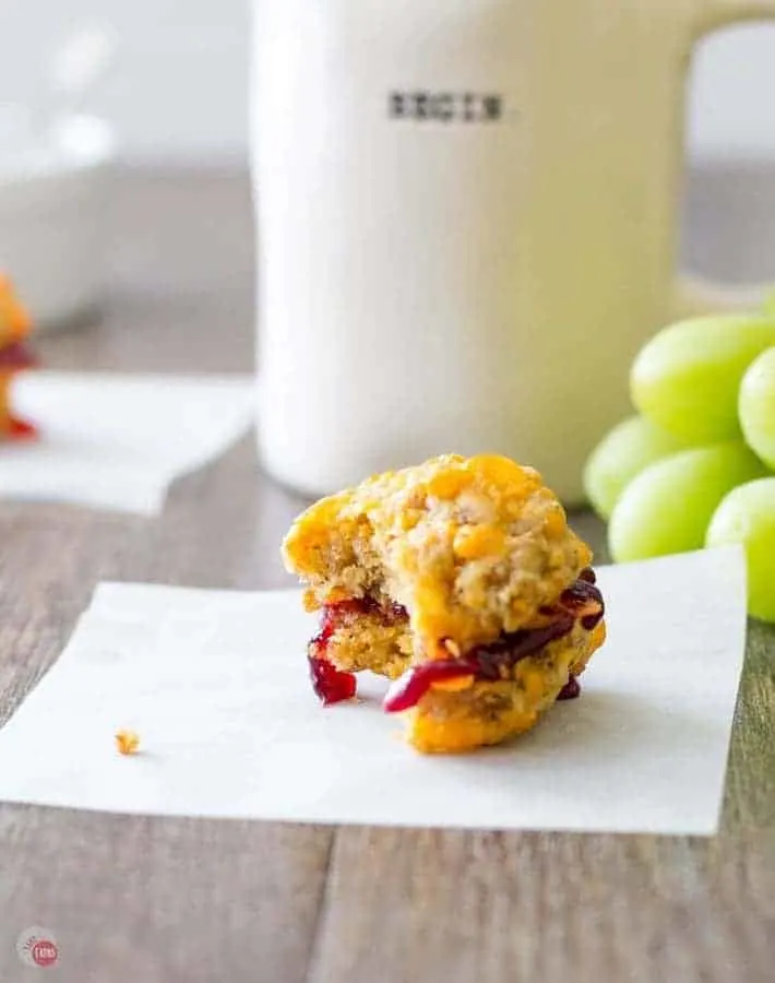 Sausage ball sliders with jelly filling on a white napkin with grapes on a wood surface