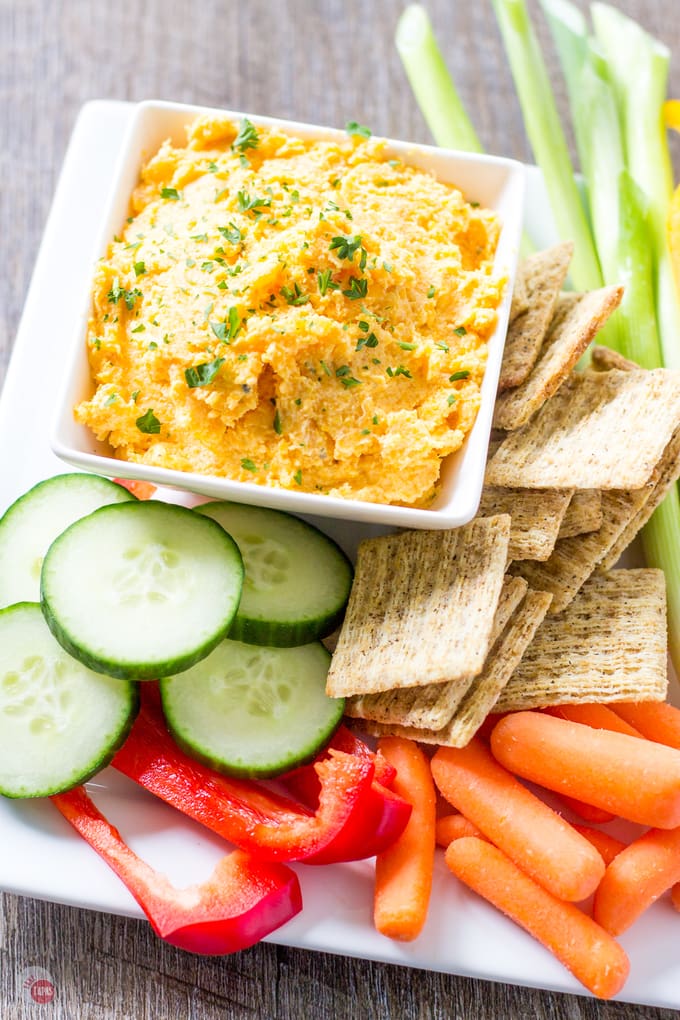 Ovverhead of Butternut Squash Dip with Garlic and Herbs in a white bowl and crackers and veggies all on a white platter.