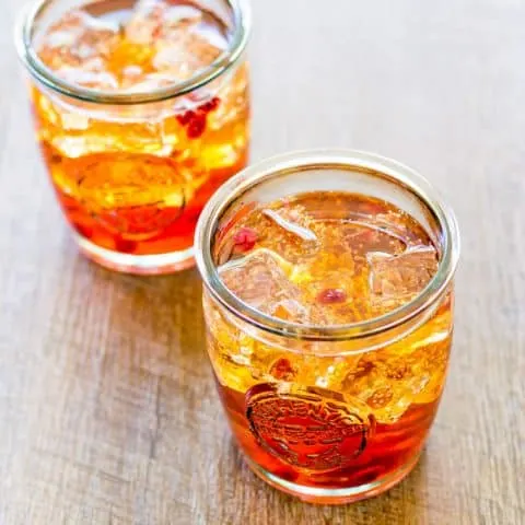 Overhead of 2 Sunrise Spritzer with Pomegranate and Orange on a wooden surface