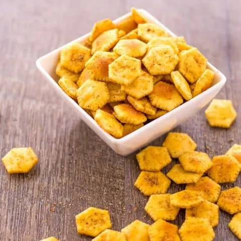 Jerk Spiced Oyster Crackers in a white bowl and spilled out on a wood surface.
