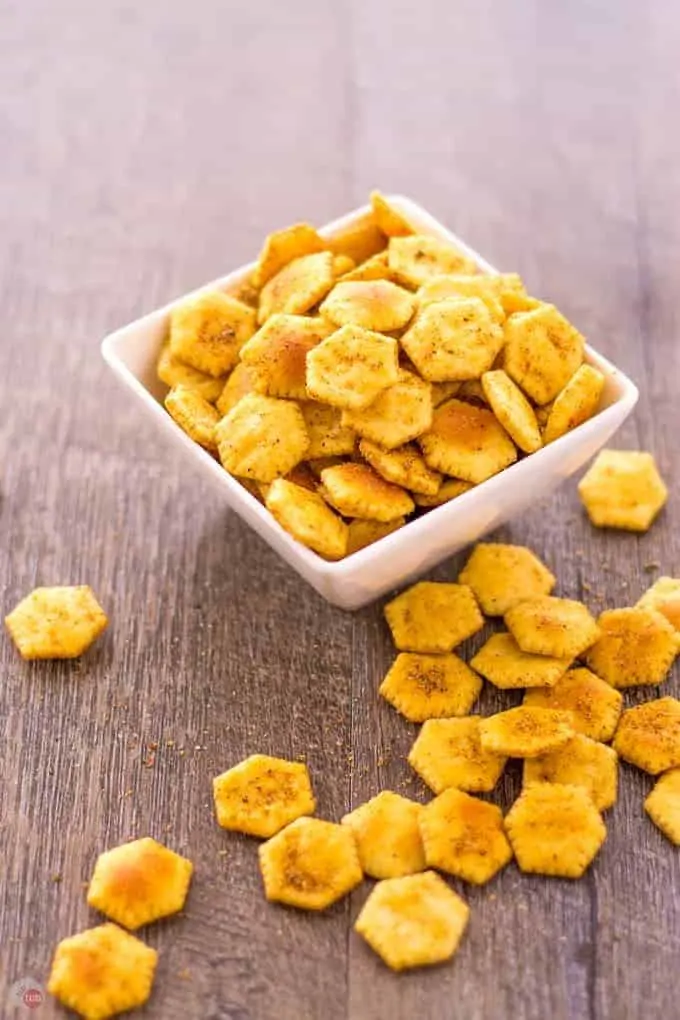 Jerk Spiced Oyster Crackers in a white bowl and spilled out on a wood surface.