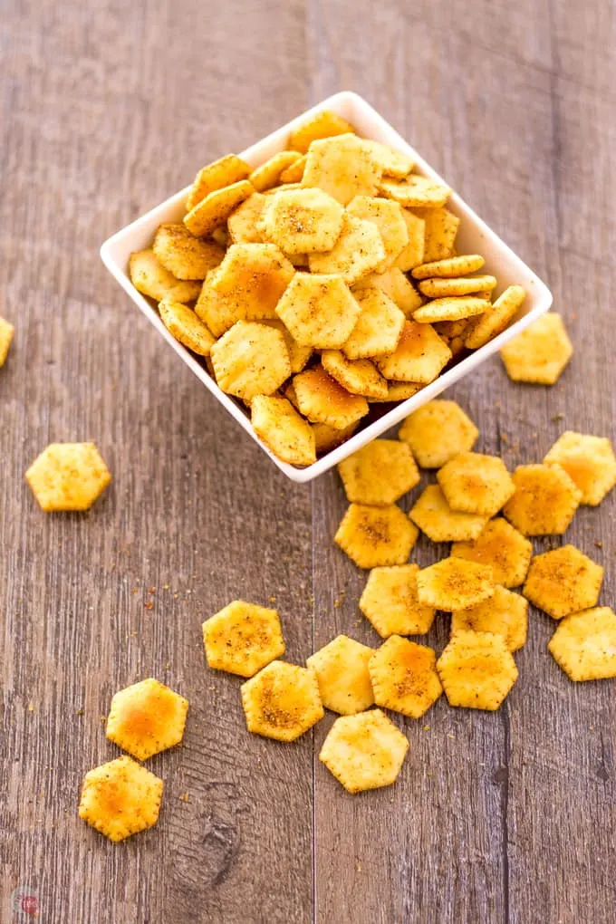 overhead of Jerk Spiced Oyster Crackers in a whiite bowl and spilled out on to a wood surface.