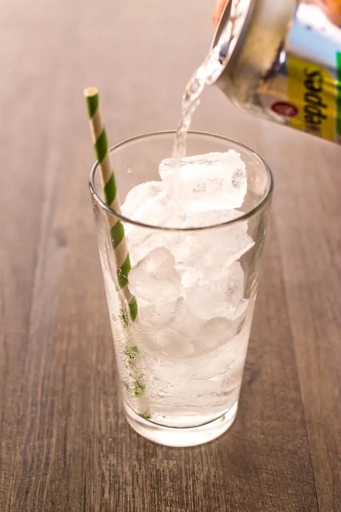 Pouring the schweppes in to a glass of ice